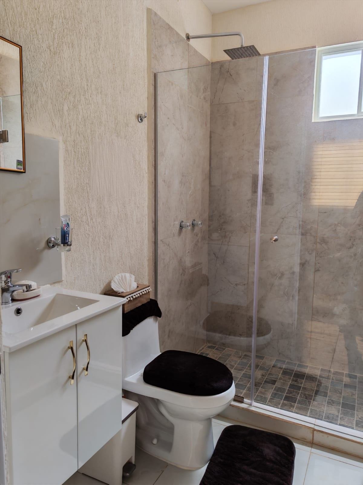Baño completo con regadera de cristal templado, escusado y lavabo con mueble blanco