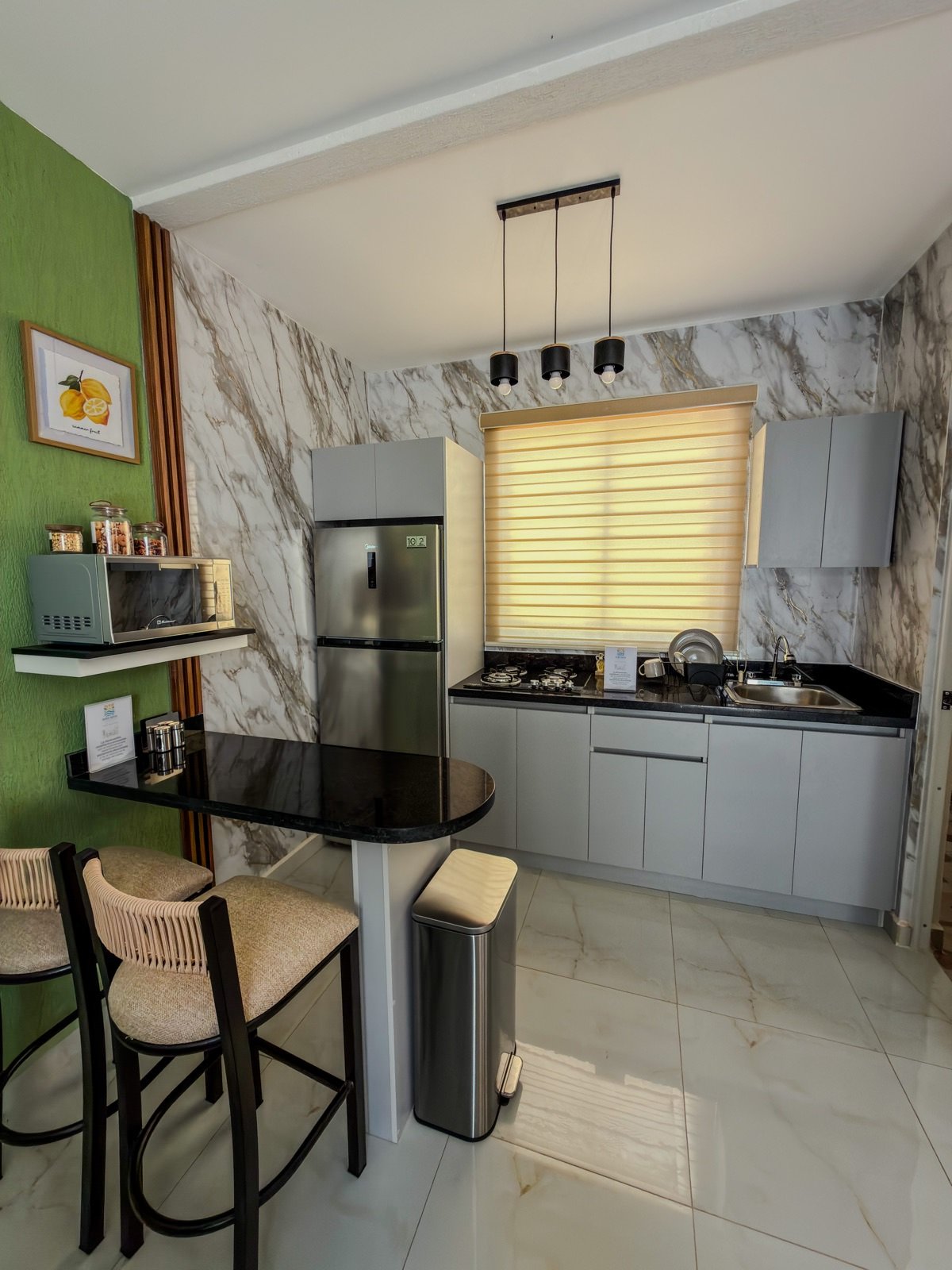 Cocina con refrigerador, microondas, estufa, fregadero y barra desayunadora con banca