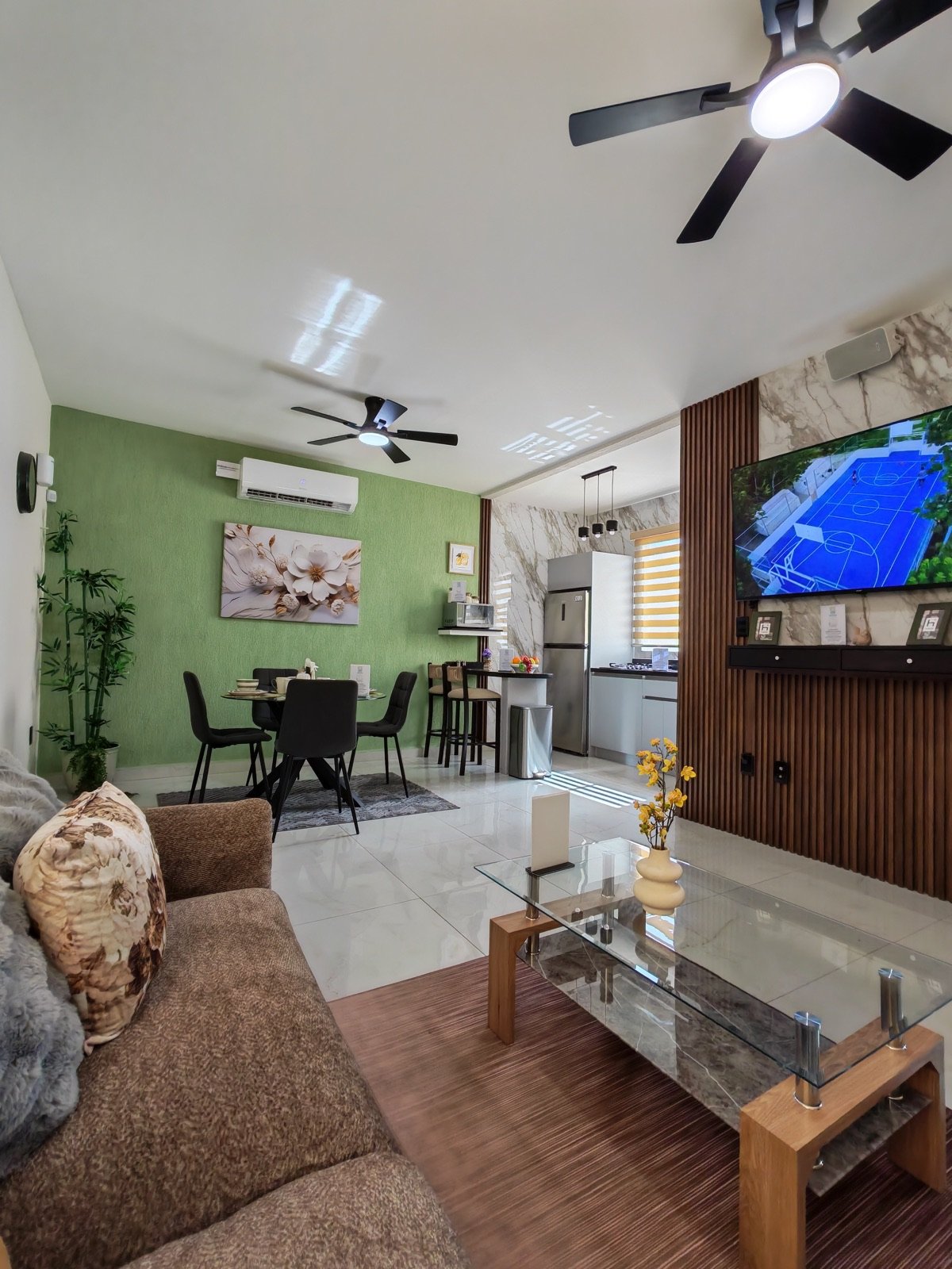 Sala con sofá en primer plano y vista hacia el comedor y la cocina del departamento muestra Aura Mar